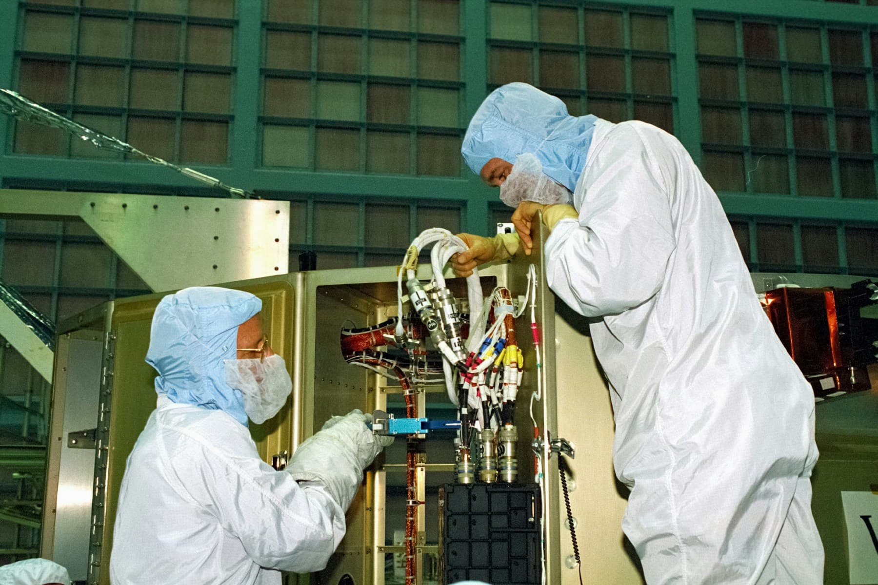 Clean-room technicians working on controlled aerospace hardware